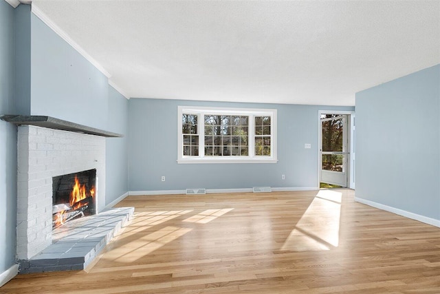 unfurnished living room with light wood-type flooring, a textured ceiling, and a fireplace