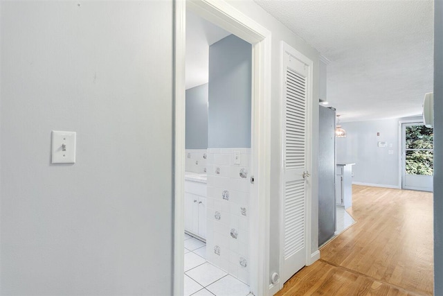 hall featuring a textured ceiling and light hardwood / wood-style flooring