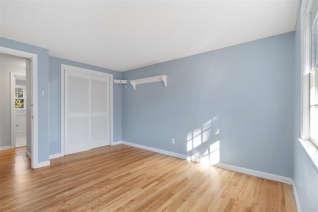 unfurnished bedroom with light wood-type flooring and a closet