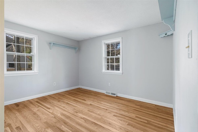 spare room featuring light wood-type flooring and a textured ceiling