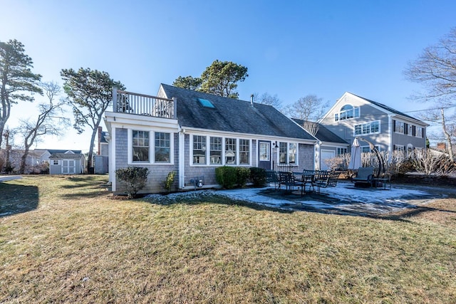 view of front of house with a balcony, a patio, a storage shed, and a front yard