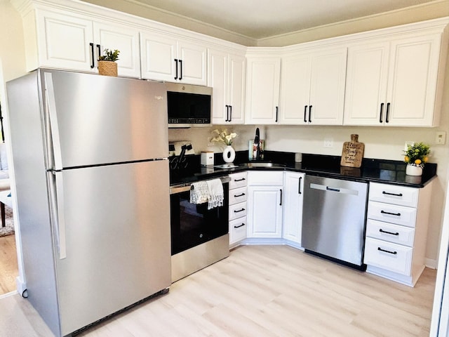 kitchen featuring stainless steel appliances, light wood finished floors, white cabinetry, and ornamental molding