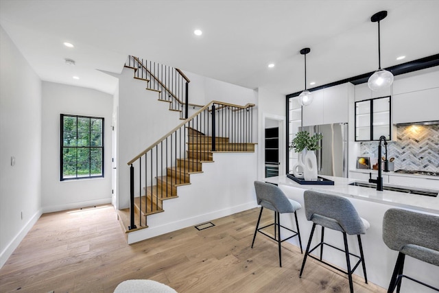 2 Buttercup Ln, South Yarmouth, MA 02664 - kitchen with stainless steel refrigerator, a kitchen bar, white cabinetry, hanging light fixtures, and decorative backsplash