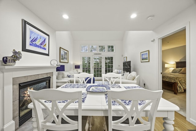 dining space with a tiled fireplace and light wood-type flooring