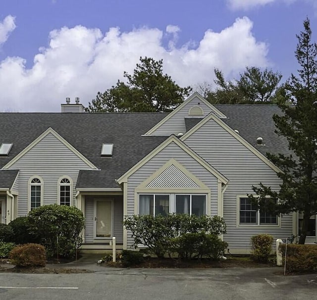 view of front of home featuring a chimney and a shingled roof