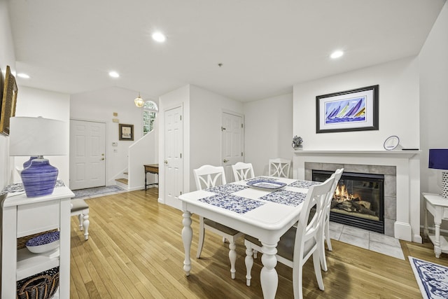 dining space with hardwood / wood-style floors and a tile fireplace