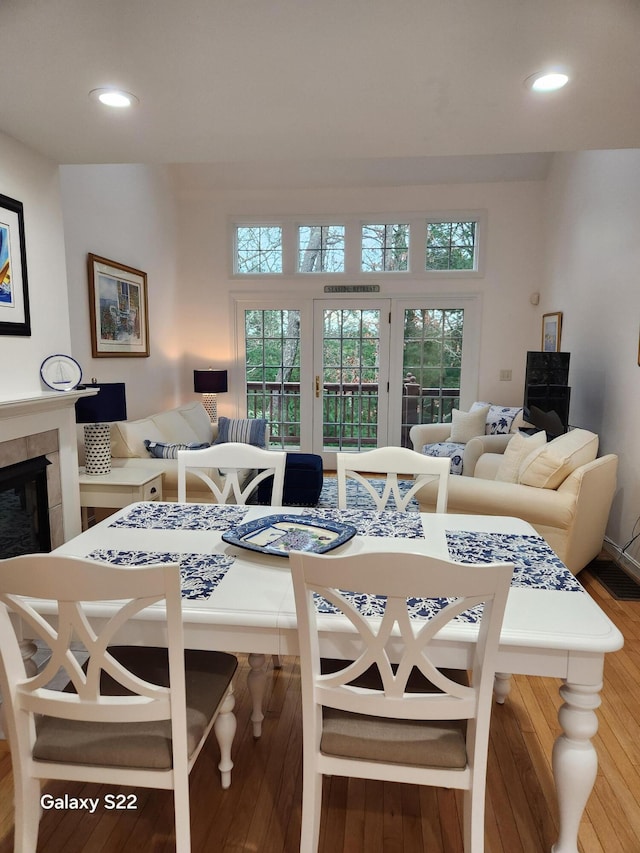 dining space with recessed lighting, plenty of natural light, a fireplace, and hardwood / wood-style flooring