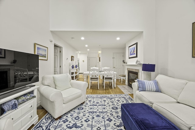 living room featuring recessed lighting, a tile fireplace, and light wood-style floors