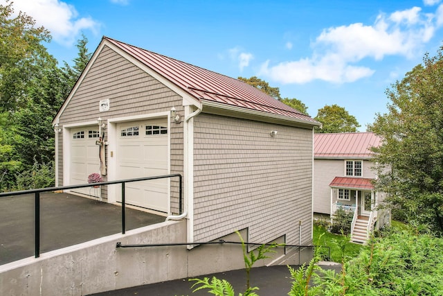 view of home's exterior with a standing seam roof, an outdoor structure, metal roof, and a garage