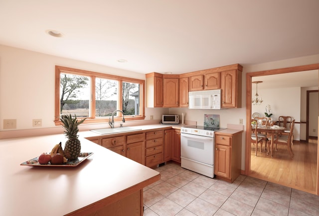 kitchen with sink, white appliances, light tile patterned floors, and a chandelier