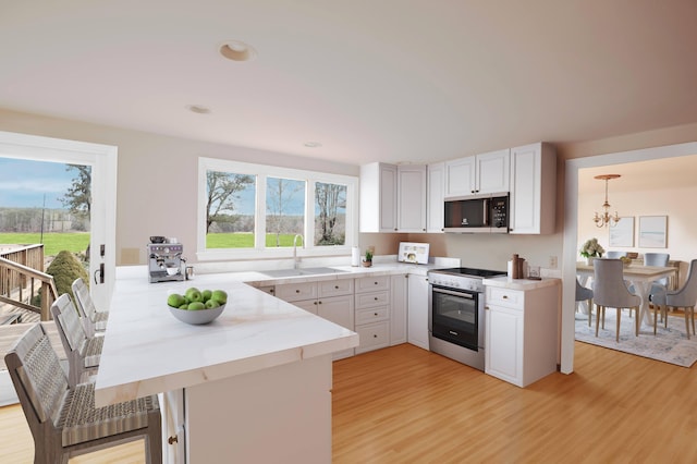 72 Lookout Rd, Yarmouth Port, MA 02675 - kitchen with black microwave, stainless steel range with gas stovetop, a peninsula, and light wood-type flooring