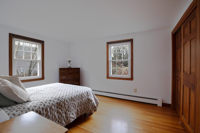 bedroom with a baseboard radiator and light hardwood / wood-style floors