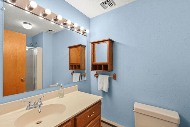 bathroom with a shower with shower door, a textured ceiling, toilet, and vanity