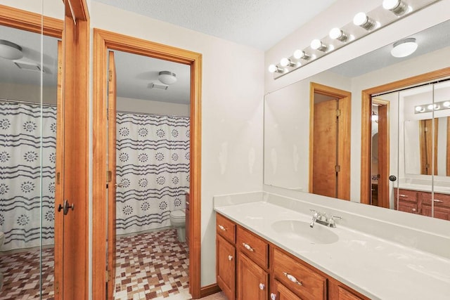 bathroom featuring a textured ceiling, toilet, vanity, and walk in shower