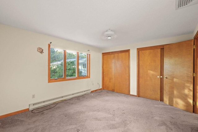 unfurnished bedroom featuring ceiling fan, light colored carpet, a baseboard heating unit, and two closets