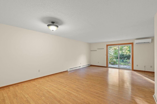 spare room featuring a wall mounted air conditioner, light hardwood / wood-style flooring, and a baseboard heating unit