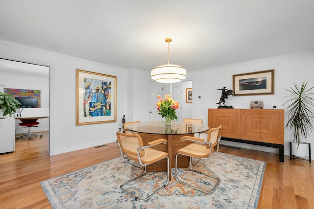 dining space with crown molding, light wood-style floors, visible vents, a baseboard heating unit, and baseboards