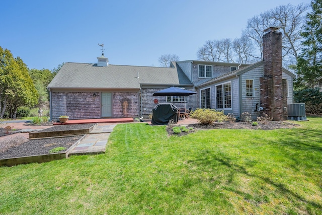 back of house with a lawn, a chimney, central air condition unit, and a patio