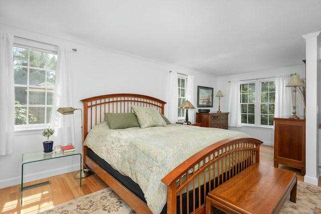 bedroom featuring ornamental molding, visible vents, wood finished floors, and baseboards