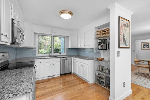 kitchen featuring light wood-style flooring, stainless steel appliances, a sink, white cabinetry, and crown molding
