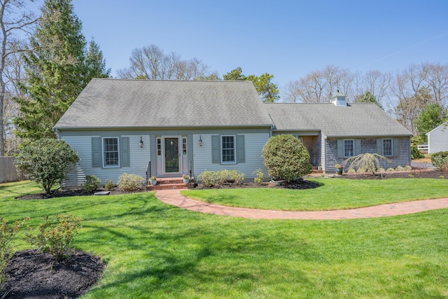 view of front of home featuring roof with shingles, a chimney, and a front yard