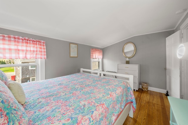 bedroom with wood finished floors, crown molding, multiple windows, baseboards, and lofted ceiling