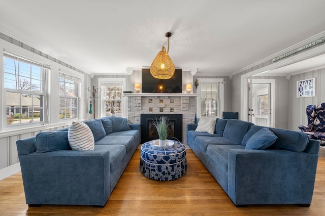 living area with crown molding, wood finished floors, and a brick fireplace