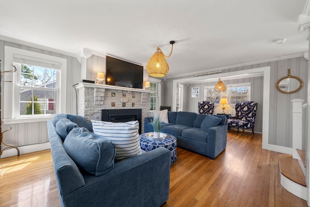 living area with crown molding, a brick fireplace, and light wood-style floors