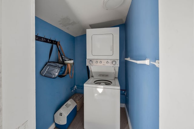 laundry room with estacked washer and dryer and baseboards