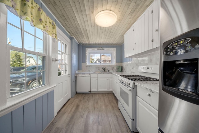 kitchen with white appliances, a sink, wooden ceiling, white cabinets, and decorative backsplash