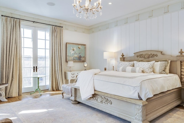 bedroom featuring a notable chandelier, hardwood / wood-style flooring, ornamental molding, and french doors