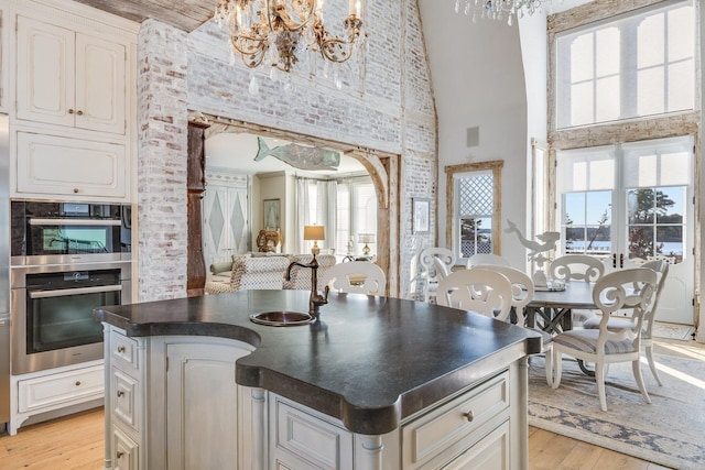 kitchen with white cabinetry, a center island, an inviting chandelier, and high vaulted ceiling