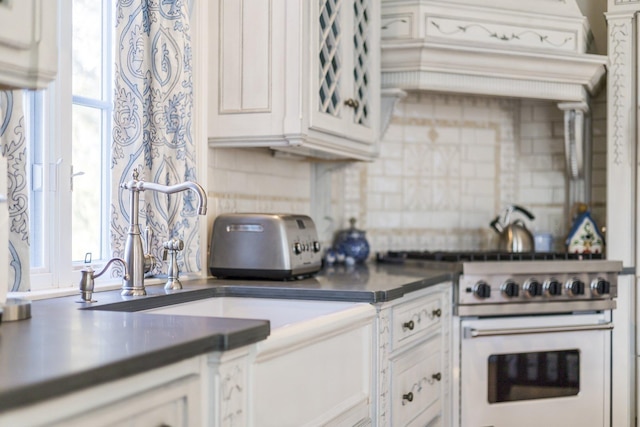 kitchen with white cabinetry, backsplash, and gas stove