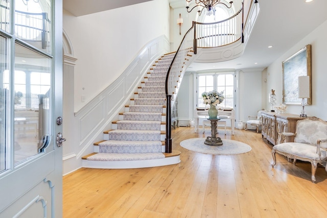 entrance foyer featuring a towering ceiling, an inviting chandelier, and light hardwood / wood-style floors