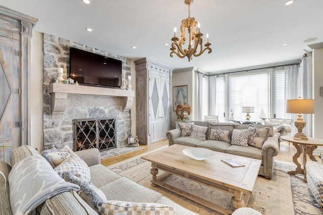 living room featuring an inviting chandelier, ornamental molding, a stone fireplace, and light hardwood / wood-style floors