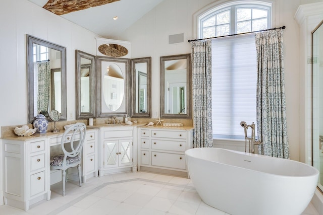 bathroom featuring tile patterned floors, a tub to relax in, vaulted ceiling, and vanity