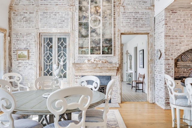 dining space with brick wall and light hardwood / wood-style floors