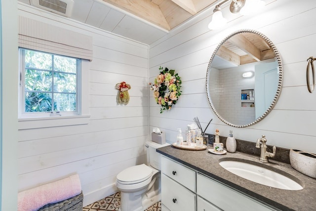 bathroom with vanity, toilet, and wood walls