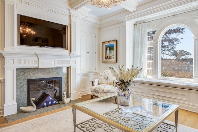 living area featuring beamed ceiling, a premium fireplace, ornamental molding, and hardwood / wood-style floors