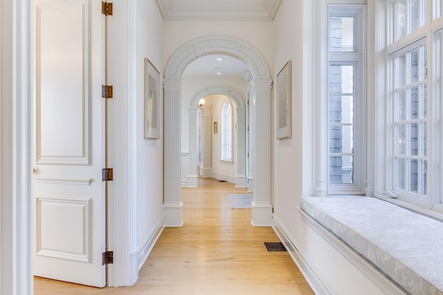 corridor with ornamental molding and light hardwood / wood-style floors