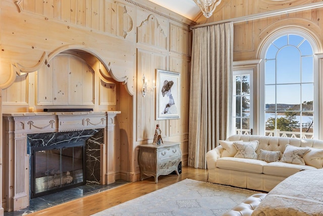 living room featuring a high end fireplace, wood-type flooring, and wood walls