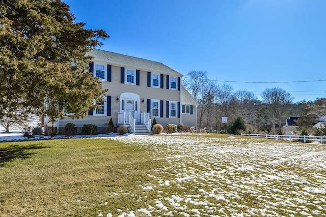 colonial-style house featuring a front yard and fence