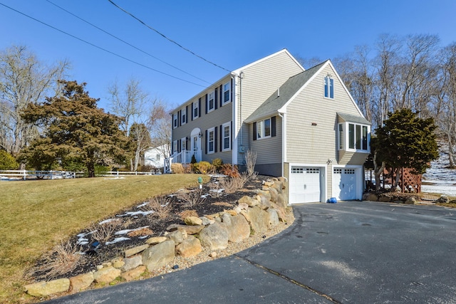 view of home's exterior featuring aphalt driveway, fence, a garage, and a lawn