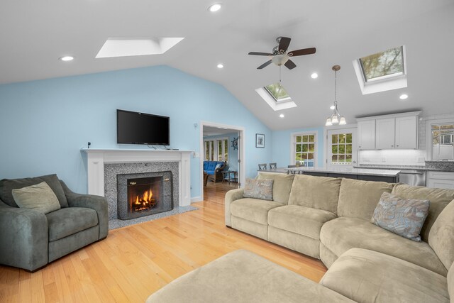 359 Lake Elizabeth Dr, Centerville, MA 02632 - living room with a skylight, a ceiling fan, lofted ceiling, light wood-style floors, and a lit fireplace