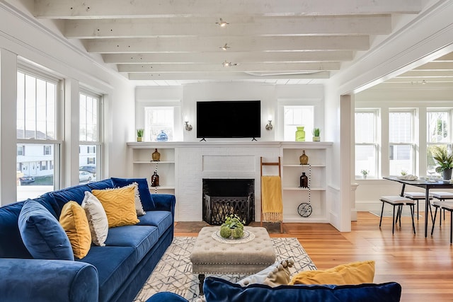 living room with beamed ceiling, light wood-type flooring, and a wealth of natural light