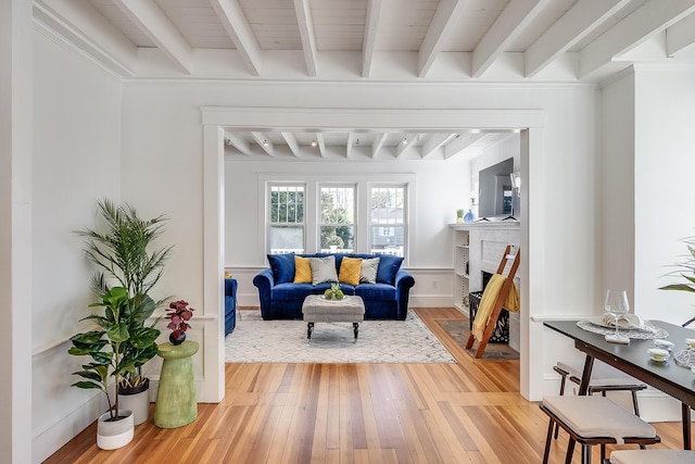 living room with beamed ceiling, a fireplace, baseboards, and hardwood / wood-style flooring