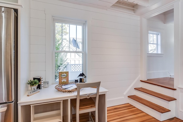 dining room featuring light wood-type flooring, stairway, and wooden walls