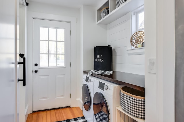 clothes washing area featuring light wood finished floors, laundry area, and washer and dryer