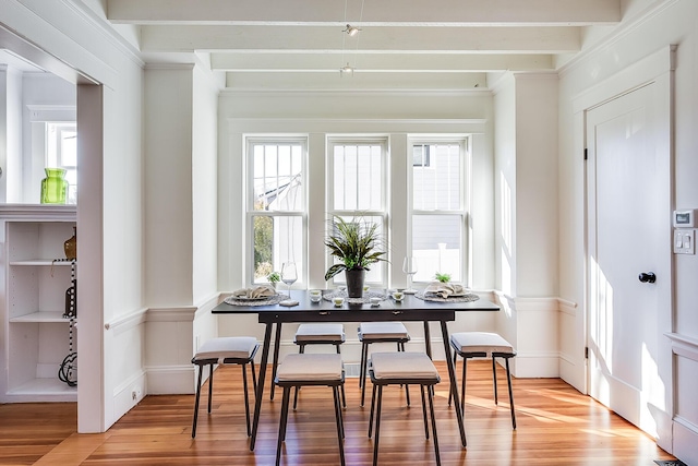 dining room with beamed ceiling and light wood-style flooring