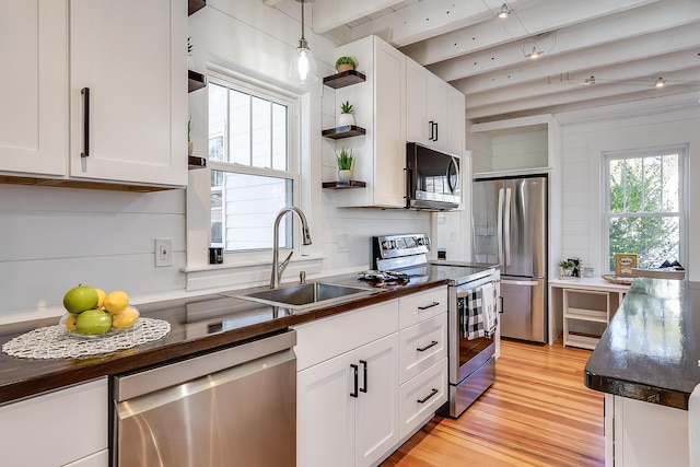 kitchen with dark countertops, a sink, stainless steel appliances, white cabinetry, and open shelves